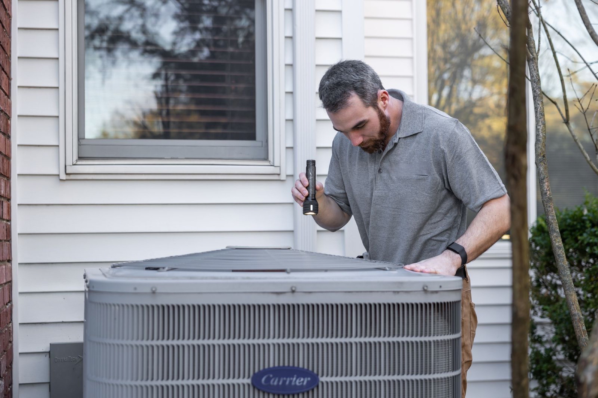 Nexis technician inspecting a home central-AC condenser